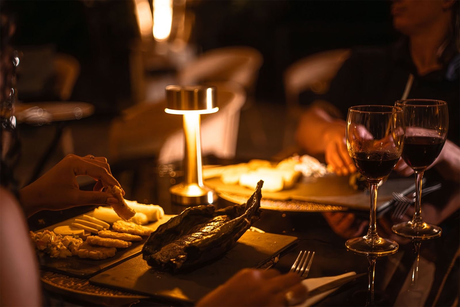 Maito servido en hoja de bijao, con yuca, patacones y vino a la luz de la lámpara