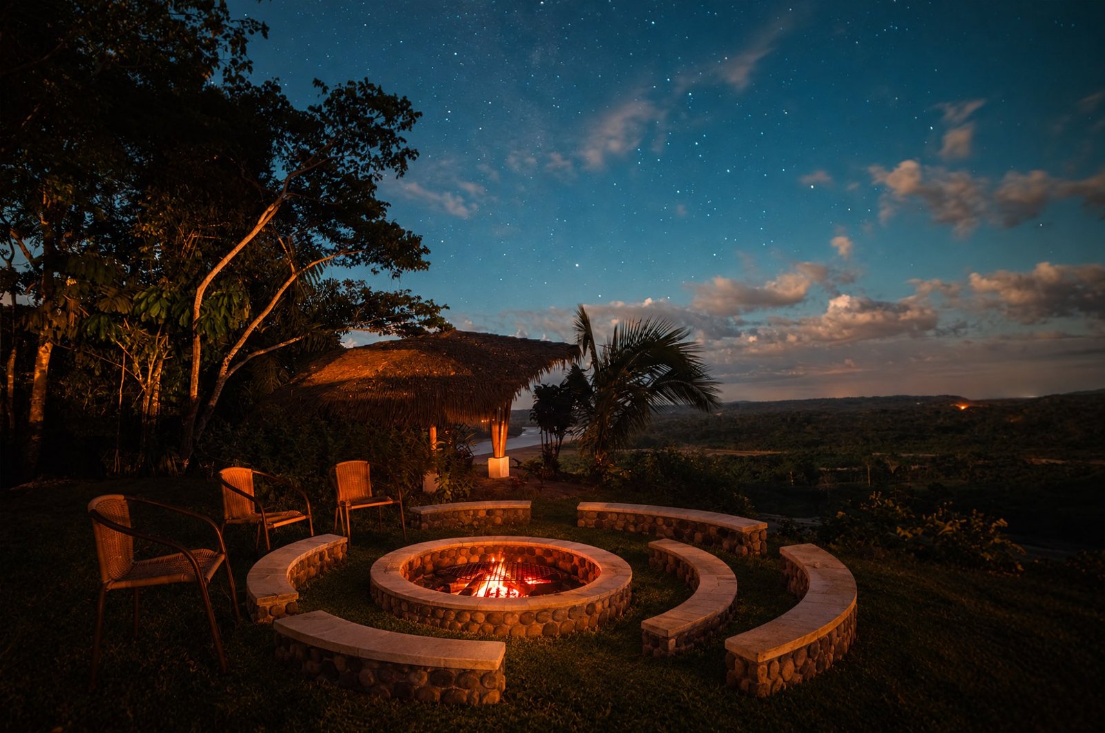 Fogata con bancas de piedra bajo el cielo estrellado, con vista al r&iacute;o Napo y la selva