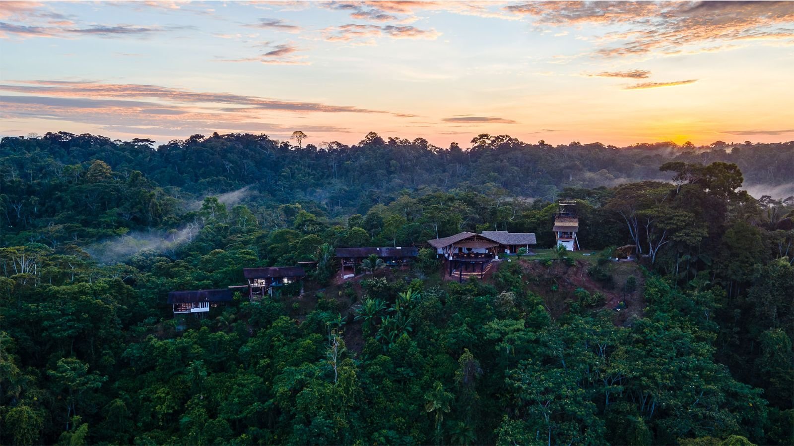 El lodge entre la selva al atardecer, con neblina en el valle
